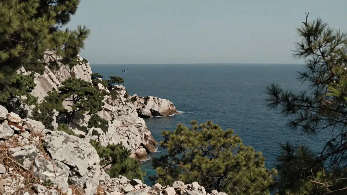 Dron volando a lo lejos sobre una costa mediterránea, ejemplo del vuelo con drones de largo alcance